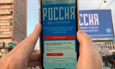 A person points a smartphone at a billboard with the words ‘Happy new year’ and the QR code in St Petersburg.