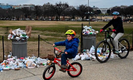 People bike past overflowing trash cans on the National Mall in Washington, DC.