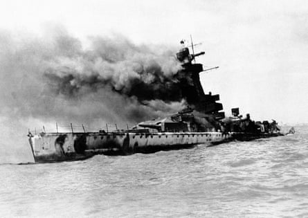 A second world war warship at sea, blowing off smoke from a fire