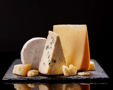 A selection of aged cheeses presented on a board, set against a dark background