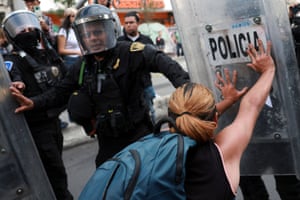 A woman pushes the riot shield of a police officer, with other officers approaching to the left