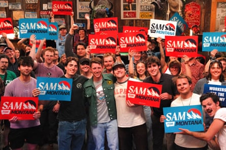 A man smiles with supporters holding his campaign signs