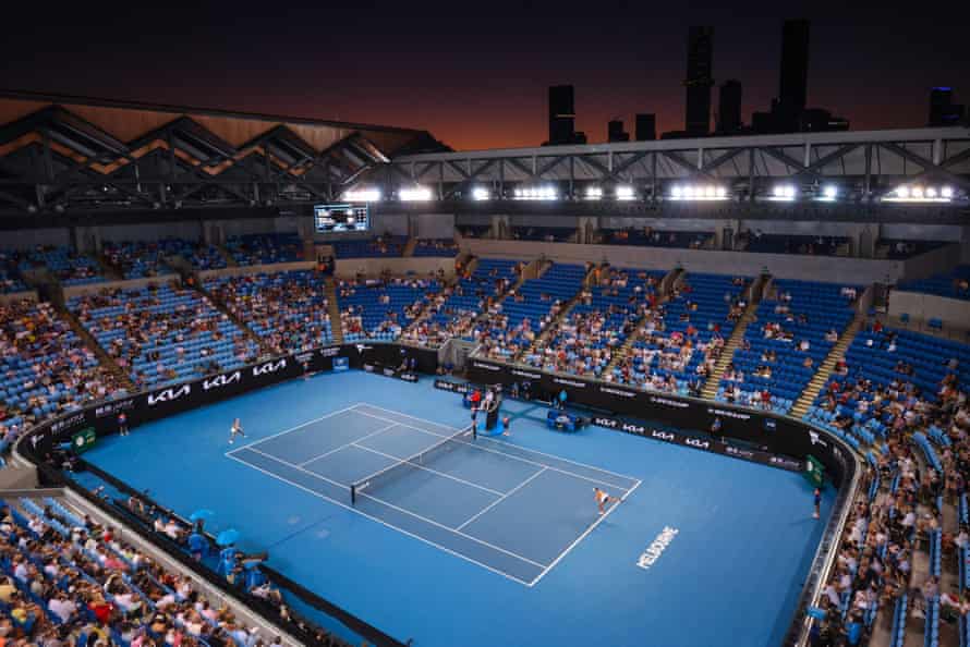 Danka Kovinic serves to Emma Raducanu during their match with the Melbourne skyline in the background.