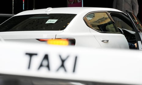 A 'taxi' sign near an Uber car