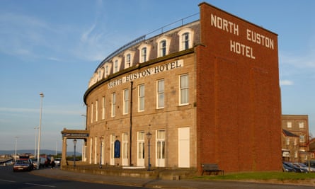 Photo de la façade d'un grand hôtel victorien en bord de mer, joliment incurvé pour correspondre à la courbe de la rue en face.  Sur le côté vierge du bâtiment, les mots de l'hôtel North Euston sont choisis en briques blanches