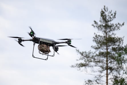 A drone flying past a tree, carrying a load