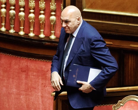 Defence minister Guido Crosetto walks down steps in the Senate chamber, holding a folder