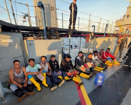 People sitting in a line, many of them wearing yellow rain boots