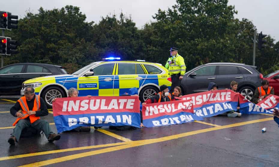 Police officers detain a protester from Insulate Britain occupying a roundabout leading from the M25 motorway  in Londo