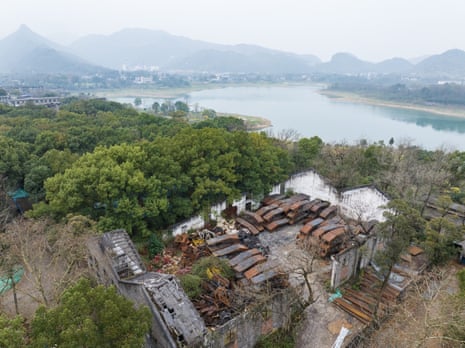 abandoned, ruined buildings in front of a river and mountains