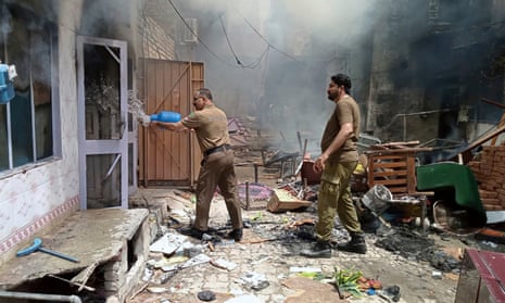 A police officer pours water into a burning house after the attack in Jaranwala on the outskirts of Faisalabad