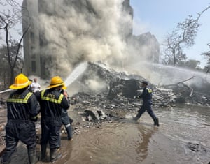 Firefighters use hoses to douse the smouldering remains of a building with water