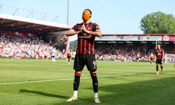 a football player holds his hands up in prayer wearing an orange mask with a spiral pattern on it and a black and red top