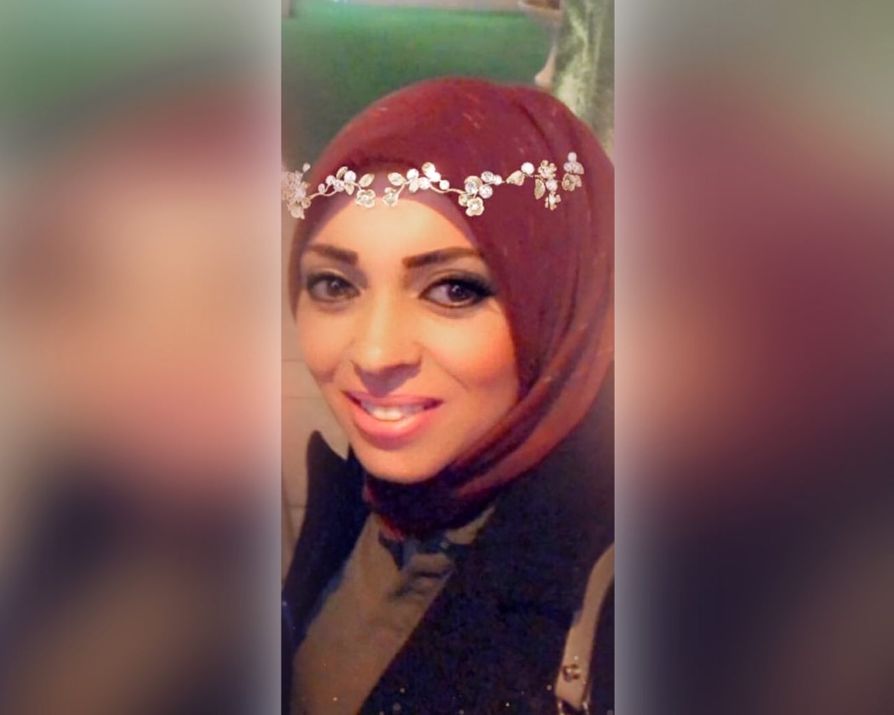 Eman, an arrested woman, smiles in a close-up wearing a maroon headscarf
