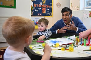 Rish Sunak with animated expression sitting at nursery table with small children