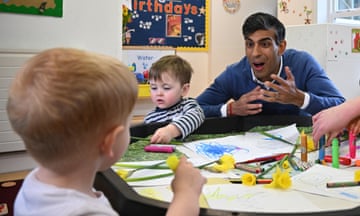 Rishi Sunak talking to young children at a table in a nursery as they do colouring in