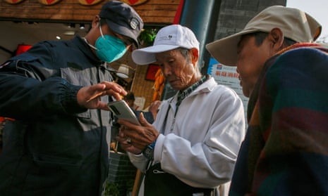 A security show an elderly man the health status app before entering a shopping district in Beijing
