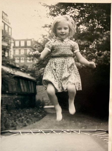 B/w photo of young fair-haired girl wearing a dress and jumping on a trampoline in her garden