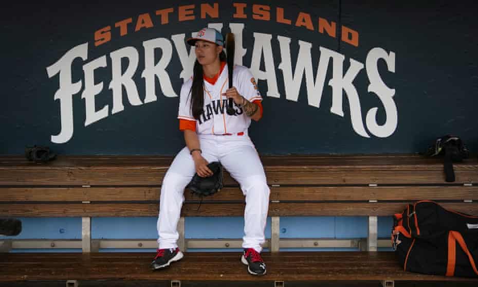 Kelsie Whitmore sits in the dugout in front of a Staten Island Ferryhawks sign.