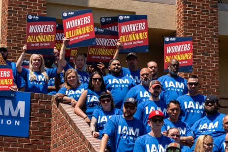 people hold signs that read 'workers vs billionaires'