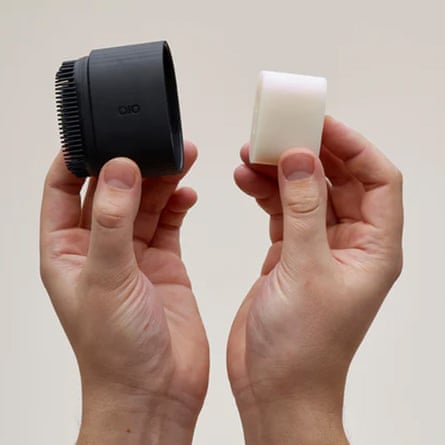 A pair of hands hold the Bob bar in its two pieces. In the left hand is the black applicator and in the right the white soap bar.