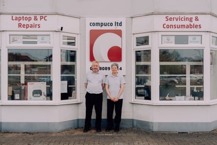 Dean and Jennifer White stand outside their computer shop, which is painted white with red writing