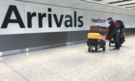 A passenger wears a mask as he arrives at Heathrow airport