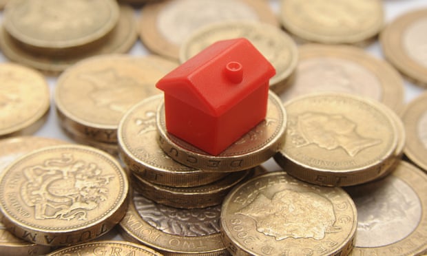 A red plastic house on top of a pile of pound coins