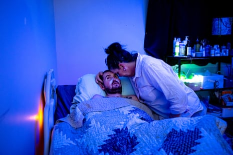 A woman kissing her adult son goodnight in a dark room with blue light