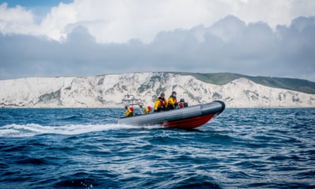 A small boat in the Channel passes the white cliffs of the south coast