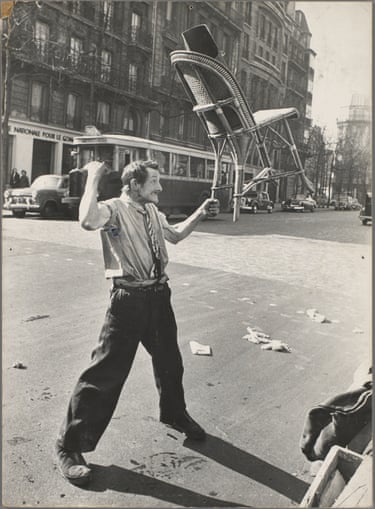 Street performer, Paris c. 1951, holding up a chair, by one leg and with one hand