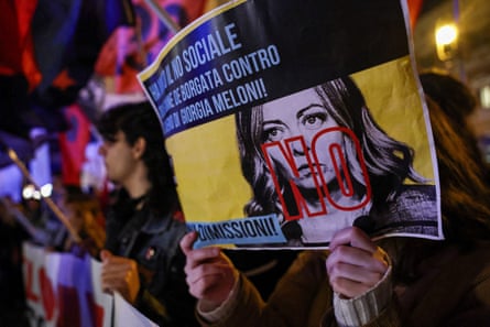 A person holds a ‘No’ poster with Meloni’s face on