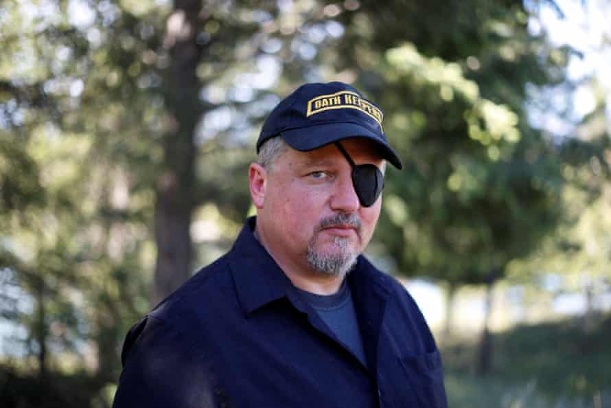 Portrait of a man wearing an eye patch and cap that says ‘Oath Keepers’ on it.