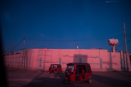 A street scene at sunset in Mogadishu. Two small tricycle taxis throw shadows on to the six-metre-high walls of a compound