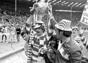 The man of the match, Brett Kenny of Wigan, holds the Challenge Cup aloft as he celebrates with fans.