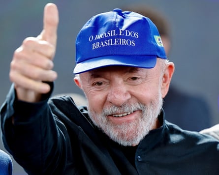 Lula wearing a blue cap and giving a thumbs-up