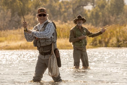 Two men in hip-waders, fishing in a river in golden light