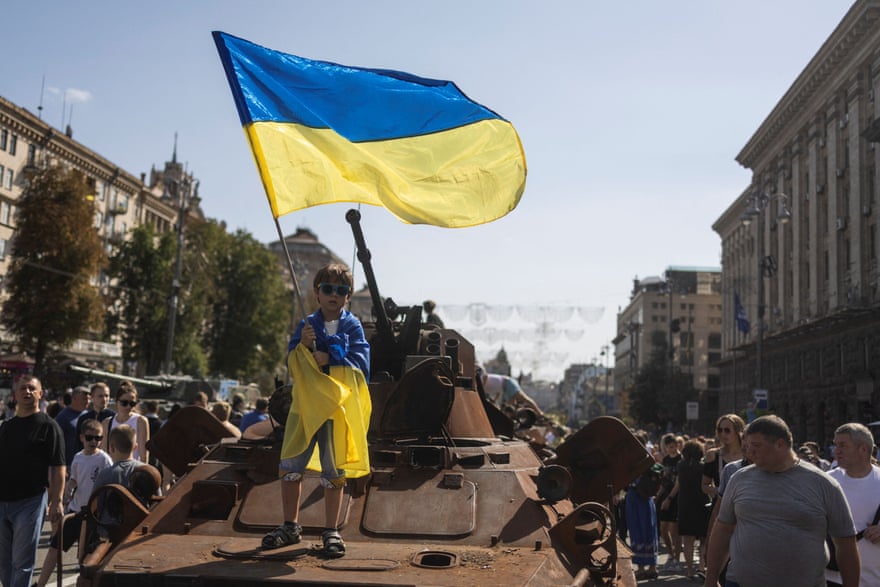 Un garçon agite un drapeau national au-dessus d'un char russe confisqué à Kyiv