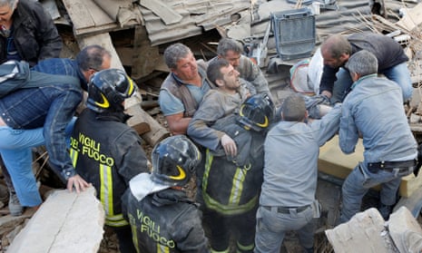 A man is carried away after having been rescued alive from the ruins following an earthquake in Amatrice