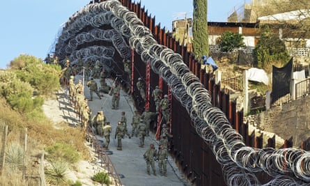 US army troops place additional concertina wire to the border fence on a hillside above Nelson Street in downtown Nogales in 2019.