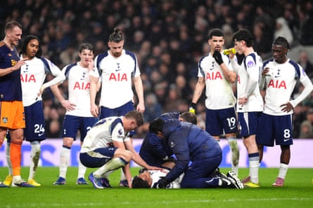 Spurs players stand around and talk as Odobert is tended to by the physio