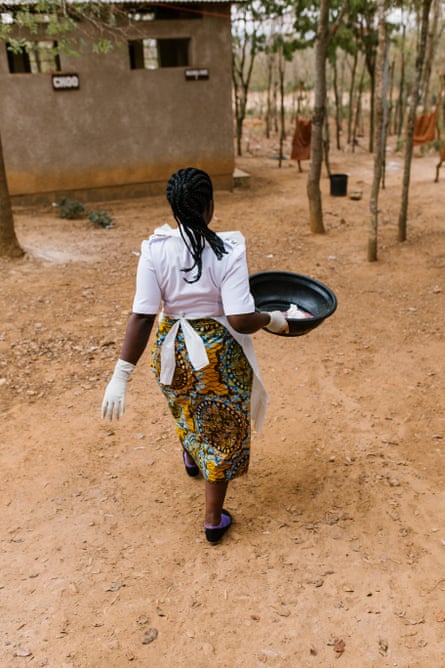 Nurse-midwife Jackeline Gideon Mwiguta carries the placenta and other waste out to the clinic’s disposal pit