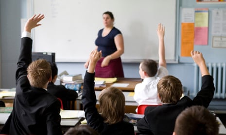 Pupils put their hands in the air to answer a question in a lesson