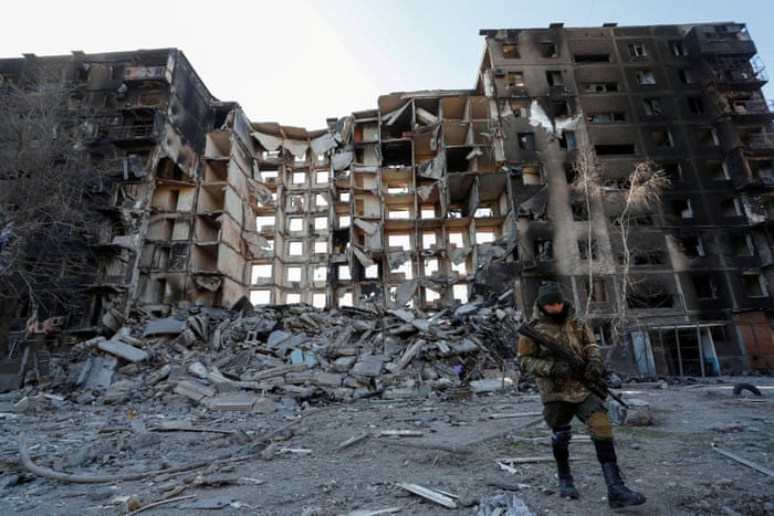 A service member of pro-Russian troops walks near an apartment building destroyed in the besieged southern port city of Mariupol, Ukraine.
