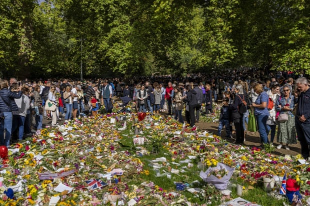 Les gens regardent les fleurs et les messages placés pour la reine Elizabeth II au mémorial de Green Park à côté du palais de Buckingham.