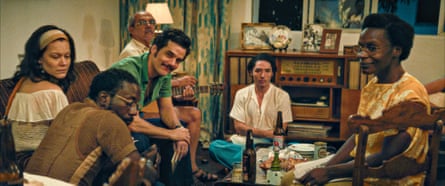 Wagner Moura and other actors sitting in a 1970s-style living room