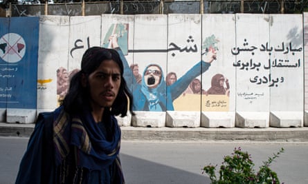 A man walks past a vandalised mural depicting a group of women in Kabul