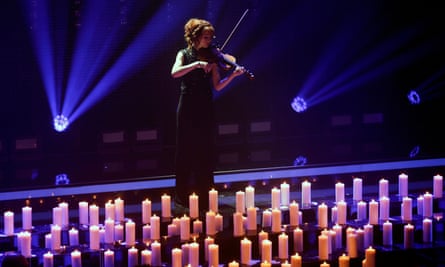 Lindsey Stirling playing violin in front of candles