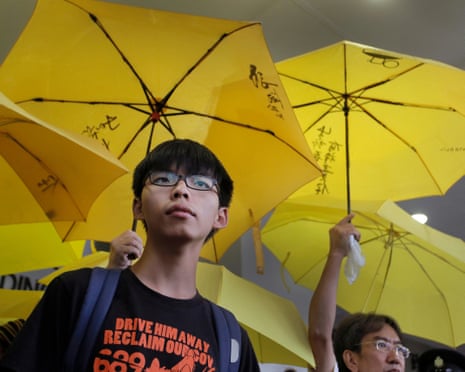 Pro-democracy activist Joshua Wong stands under yellow protest umbrellas outside a courthouse