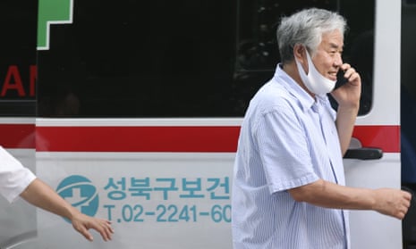 The Rev. Jun Kwang-hun - mask pulled down to his chin - boards an ambulance for treatment after being tested for coronavirus.